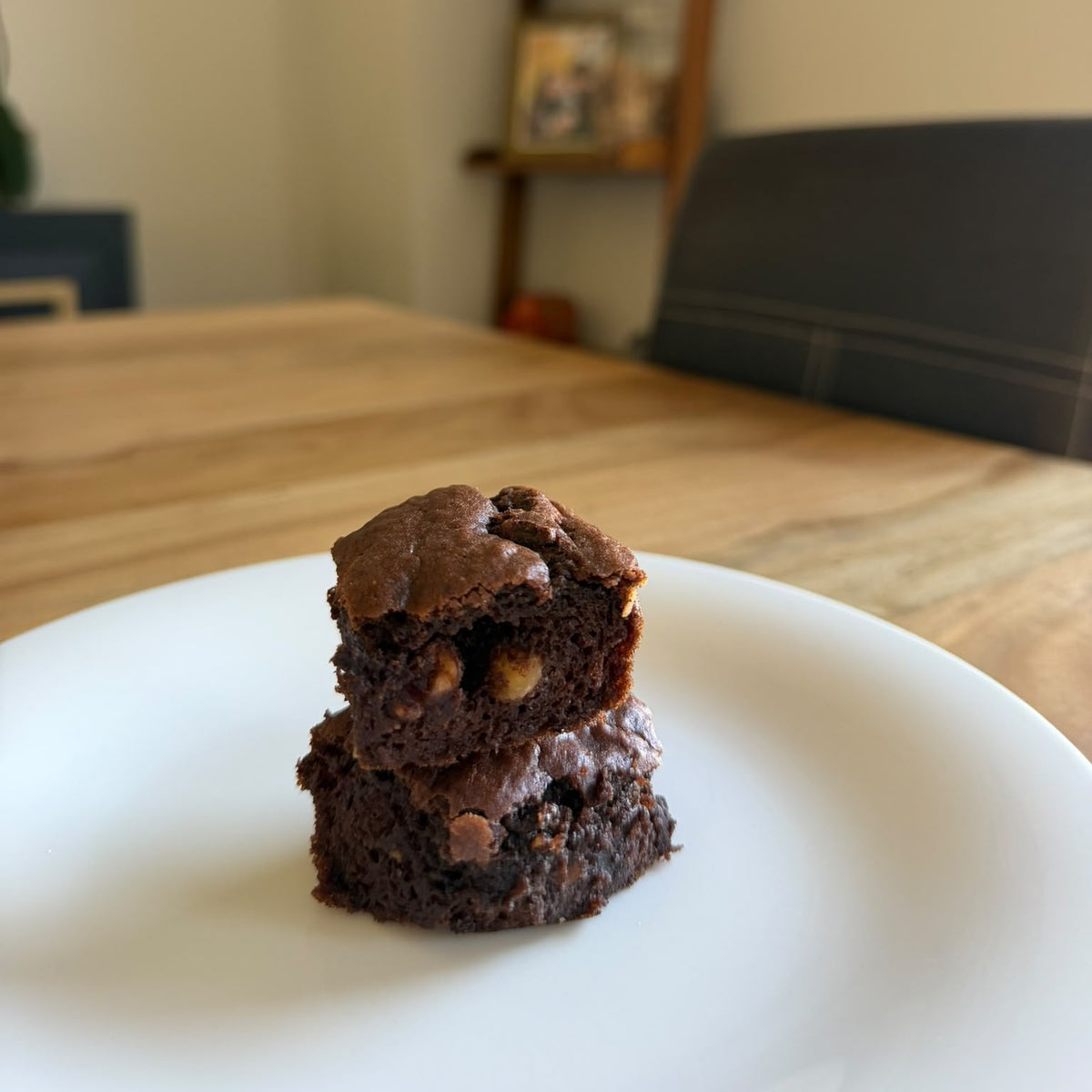 Dos porciones de brownie de crema de almendras con trozos de frutos secos, en un plato blanco